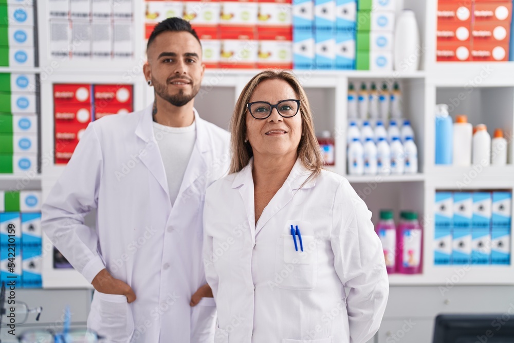 Man and woman pharmacist smiling confident standing at pharmacy