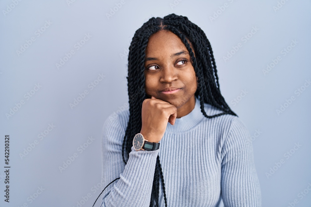 African american woman standing over blue background with hand on chin thinking about question, pensive expression. smiling with thoughtful face. doubt concept. African american woman standing over blue background with hand on chin thinking about question, pensive expression. smiling with thoughtful face. doubt concept.