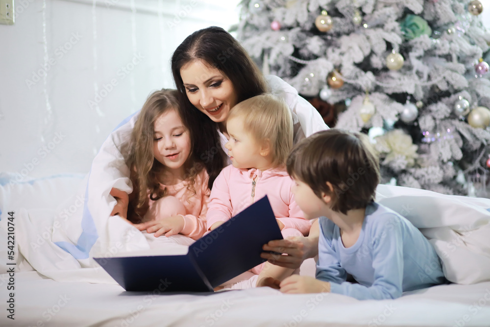 A family with children having fun on the bed under the covers during the Christmas holidays. A family with children having fun on the bed under the covers during the Christmas holidays.