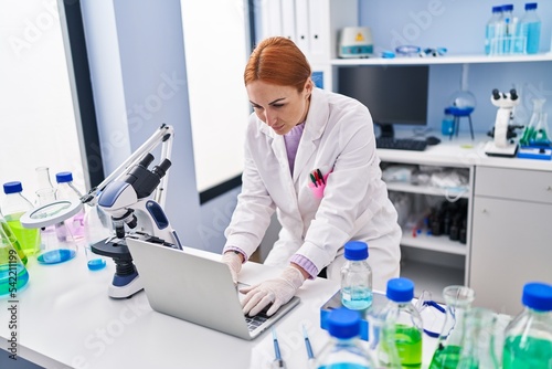 Young caucasian woman scientist using laptop working at laboratory