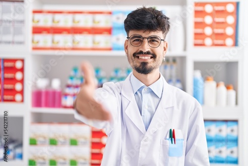 Young hispanic man pharmacist smiling confident shake hand at pharmacy © Krakenimages.com