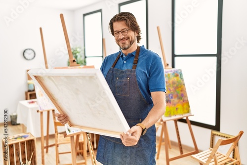 Middle age caucasian man smiling confident looking draw canvas at art studio