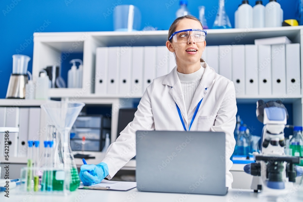 Young woman scientist smiling confident using laptop at laboratory Young woman scientist smiling confident using laptop at laboratory