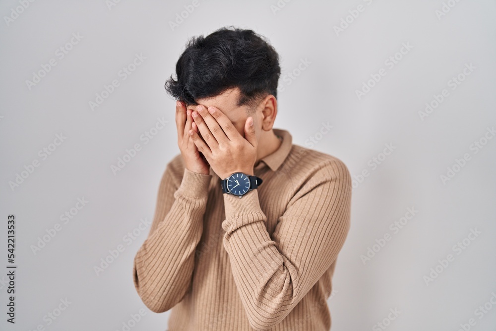 Non binary person standing over isolated background with sad expression covering face with hands while crying. depression concept. Non binary person standing over isolated background with sad expression covering face with hands while crying. depression concept.