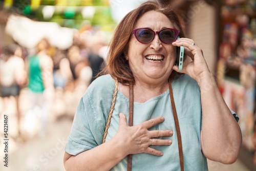 Fototapeta Naklejka Na Ścianę i Meble -  Senior woman tourist smiling confident talking on smartphone at street