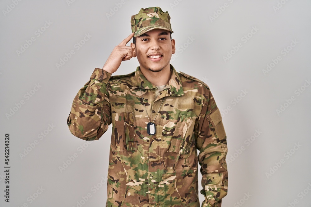 Young arab man wearing camouflage army uniform smiling pointing to head with one finger, great idea or thought, good memory Young arab man wearing camouflage army uniform smiling pointing to head with one finger, great idea or thought, good memory