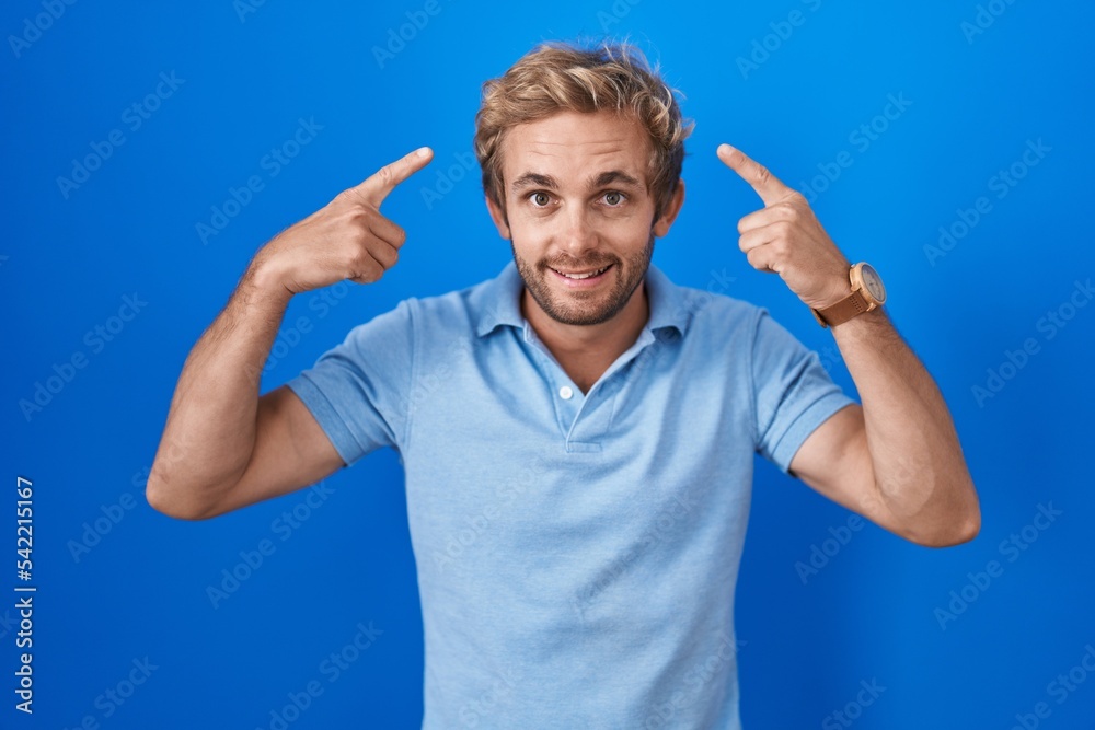 Caucasian man standing over blue background smiling pointing to head with both hands finger, great idea or thought, good memory Caucasian man standing over blue background smiling pointing to head with both hands finger, great idea or thought, good memory