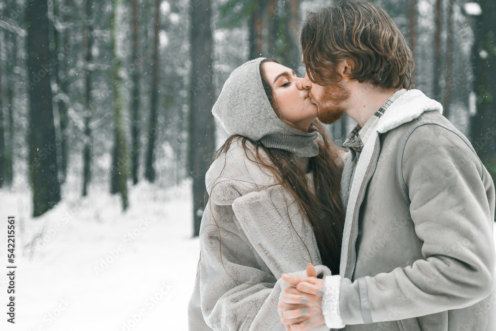 Love romantic young couple. Guy hugging kissing girl in snowy winter forest. Walking,having fun in trees, laughing. Stylish clothes,fur coat,jacket,woolen shawl. Snow lovestory. Romantic date,weekend