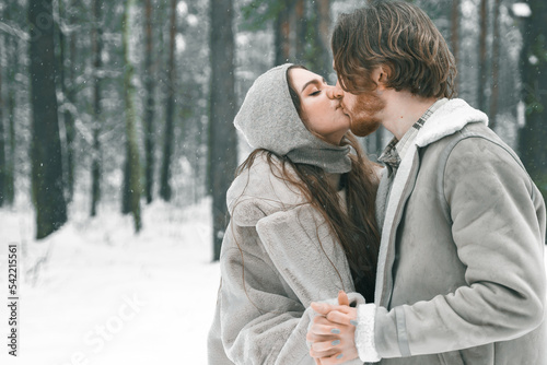 Love romantic young couple. Guy hugging kissing girl in snowy winter forest. Walking,having fun in trees, laughing. Stylish clothes,fur coat,jacket,woolen shawl. Snow lovestory. Romantic date,weekend © velirina