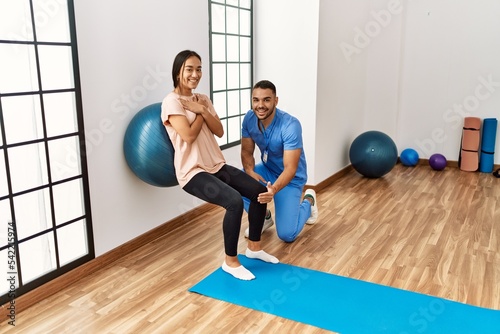 Latin man and woman wearing physiotherapist uniform having rehab session using fit ball at rehab center © Krakenimages.com