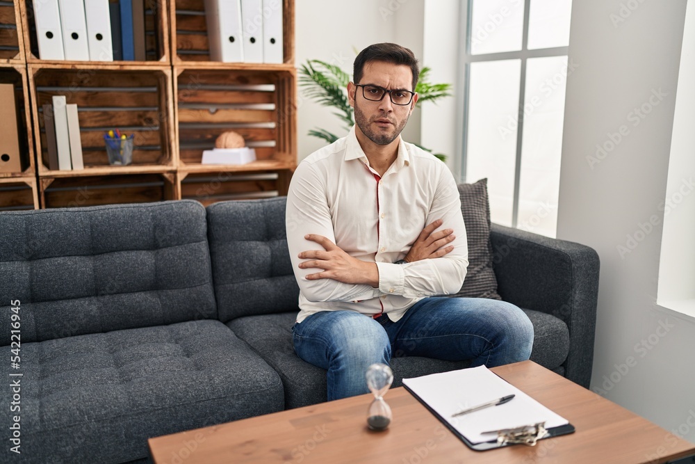 Young hispanic man with beard working at consultation office skeptic and nervous, disapproving expression on face with crossed arms. negative person. Young hispanic man with beard working at consultation office skeptic and nervous, disapproving expression on face with crossed arms. negative person.