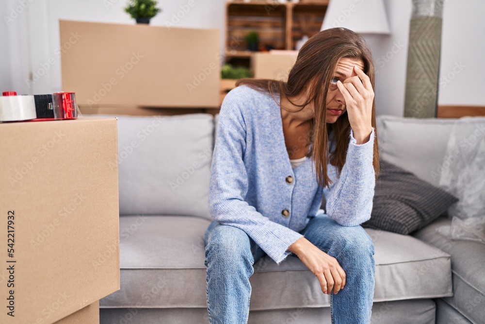 Young woman with worried expression sitting on sofa at new home Young woman with worried expression sitting on sofa at new home
