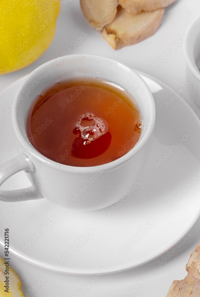 A cup of fresh tea with lemon and ginger. White background, isolated white. Close up. A cup of fresh tea with lemon and ginger. White background, isolated white. Close up.