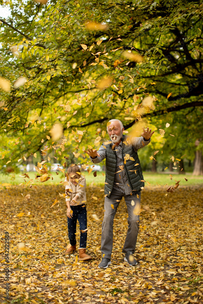 Grandfather spending time with his granddaughter in park on autumn day Grandfather spending time with his granddaughter in park on autumn day