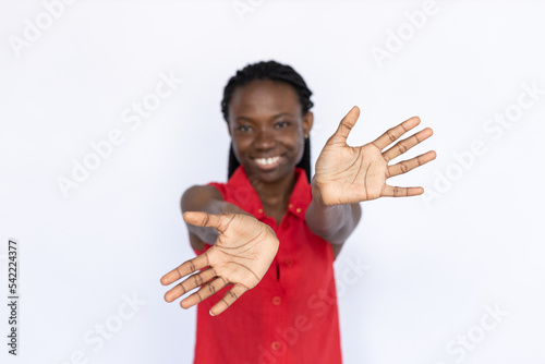 Happy woman showing open palms. Female African American model in red vest with palms facing camera. Portrait, studio shot, advertising concept.