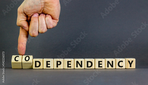 Codependency or dependency symbol. Concept words Codependency and dependency on wooden cubes. Psychologist hand. Beautiful grey background. Psychological codependency dependency concept. Copy space. photo