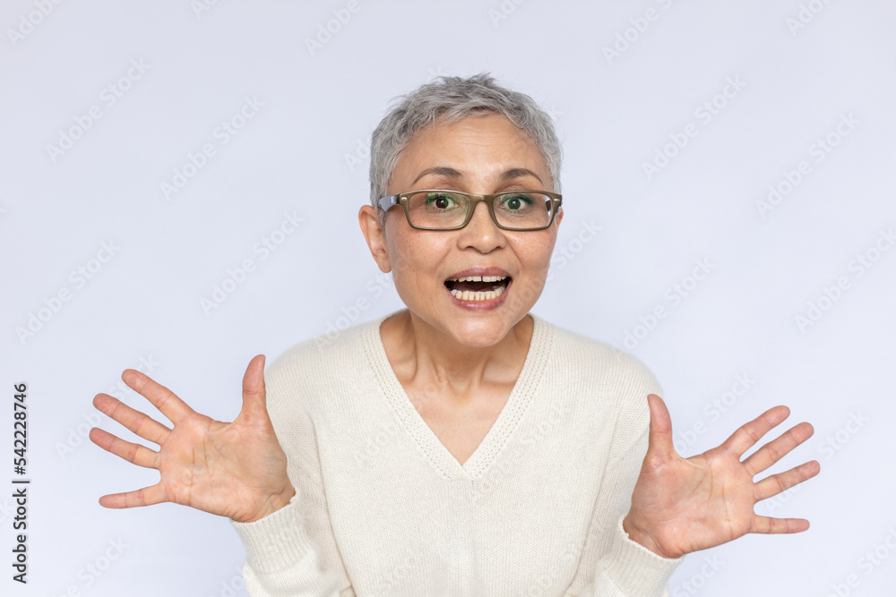 Portrait of excited senior woman standing with open mouth over white background. Mature Caucasian woman wearing eyeglasses and white jumper looking at camera in admiration. Awe and admiration concept Portrait of excited senior woman standing with open mouth over white background. Mature Caucasian woman wearing eyeglasses and white jumper looking at camera in admiration. Awe and admiration concept