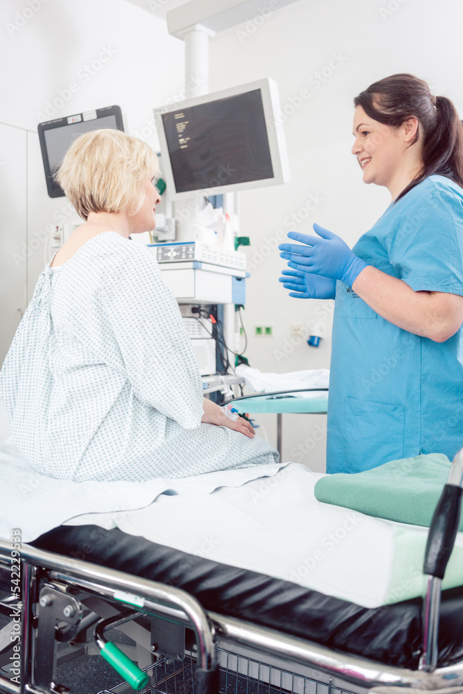 Nurse explaining procedure to patient in hospital surgery to ease anxiety Nurse explaining procedure to patient in hospital surgery to ease anxiety