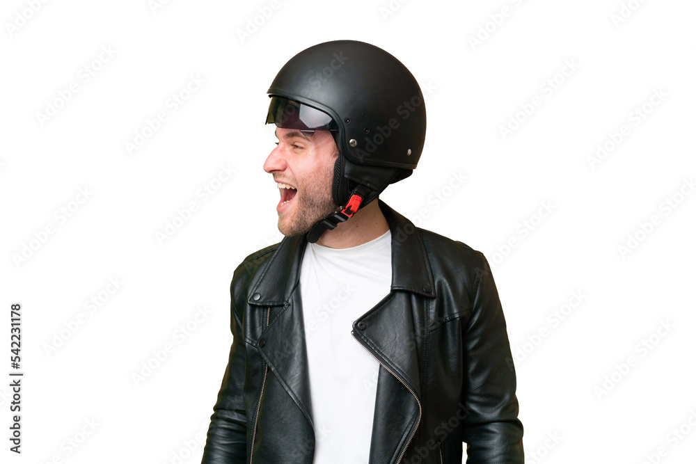 Young caucasian man with a motorcycle helmet isolated on green chroma background laughing in lateral position Young caucasian man with a motorcycle helmet isolated on green chroma background laughing in lateral position