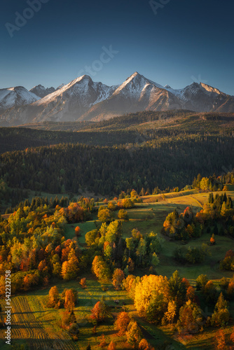Beautiful autumn with red an yellow trees under the Tatra Mountains at sunrise. Slovakia