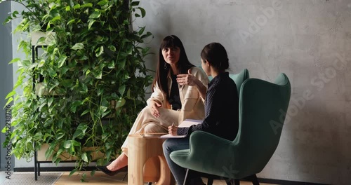 Wallpaper Mural Older and younger multi ethnic colleagues talking eaten on armchairs in modern office lobby, intern listen to guidance of middle-aged woman mentor, give advice, provide helpful information. Interview Torontodigital.ca