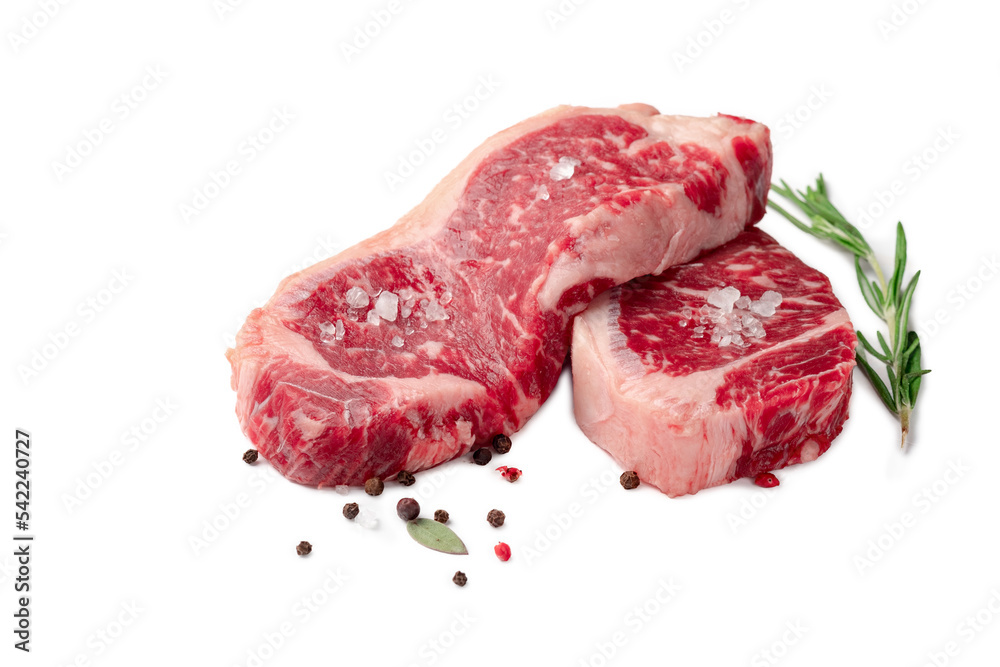 Two juicy raw beef striploin steaks isolated on a white background with herbs and spices