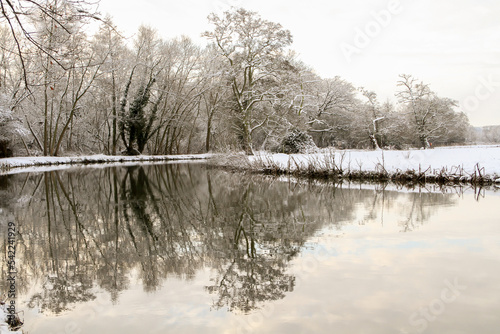 Snowy winter landscape of the Wey Navigation canal in Surrey England in golden morning light