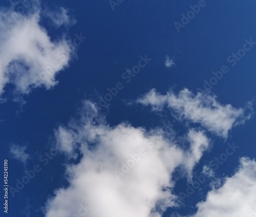 Fondo natural con detalle varias nubes de tonos blancos sobre fondo de cielo azul intenso