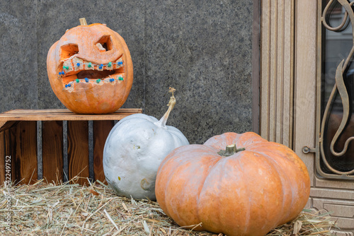 House entrance with halloween pumpkin decoration with spooky faces on porch of apartment building during all hallows eve