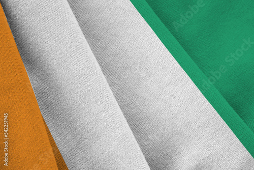 Ivory Coast flag with big folds waving close up under the studio light indoors. The official symbols and colors in banner photo