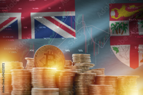 Fiji flag and big amount of golden bitcoin coins and trading platform chart. Crypto currency photo