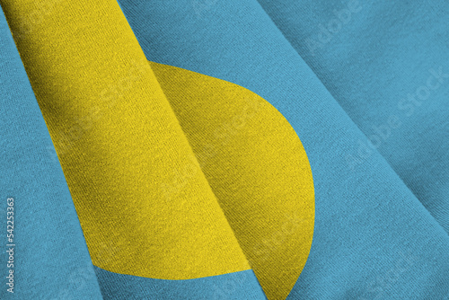 Palau flag with big folds waving close up under the studio light indoors. The official symbols and colors in banner photo