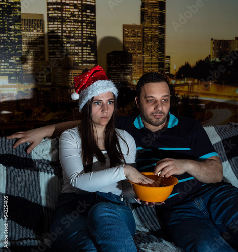 Adult girl and guy are sitting on couch and watching movie  eating popcorn. Selective focus. Picture for website about family  leisure.