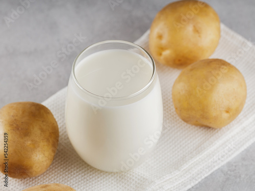 Potato milk alternative non dairy drink. Lactose free milk and raw potatoes on a gray background. Alternative milk concept