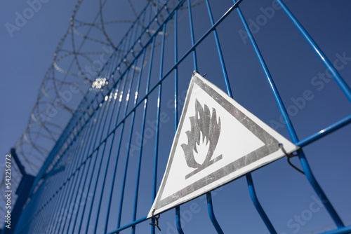 An explosion hazard sign hanging on a fence around a gas installation or gas pipeline. Selective focus. Copy space.