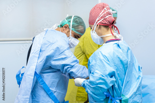 nurse in operating room dressing surgeon in pre-operative gown and gloves