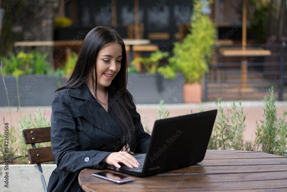 Beautiful woman working on a laptop at an outside cafe Beautiful woman working on a laptop at an outside cafe