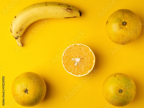 Oranges and bananas on a table with a yellow background.