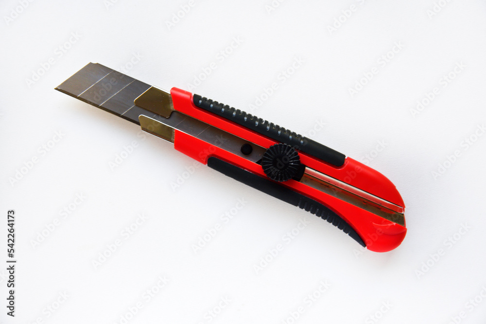 Red stationery knife with blades on a white background. Cutting tool with blades on a white background. Red stationery knife with blades on a white background. Cutting tool with blades on a white background.