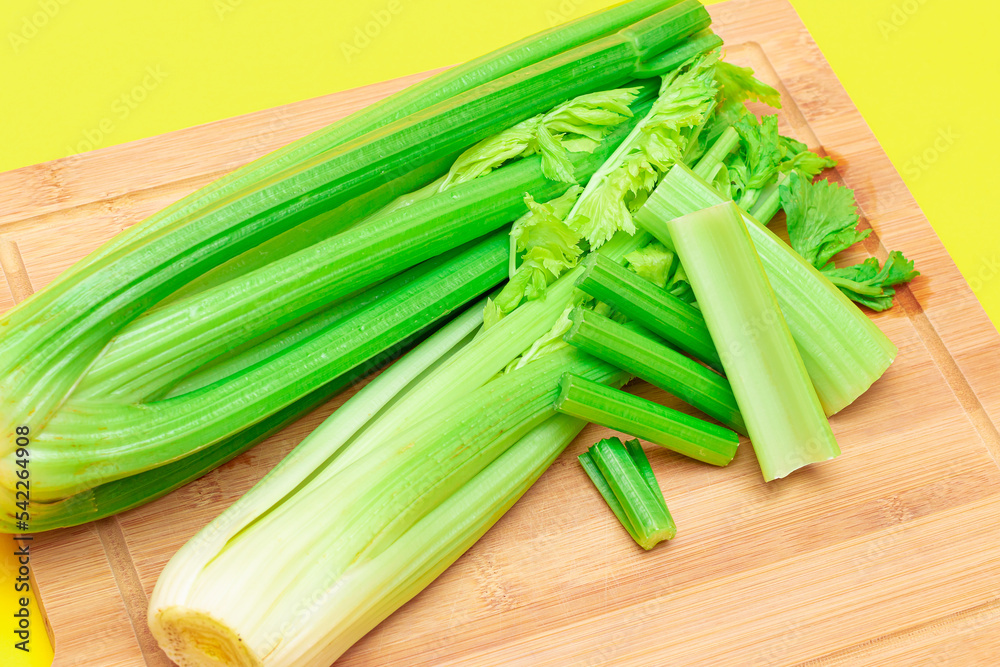 Fresh Celery Stem and Chopped Celery Sticks on Wooden Cutting Board