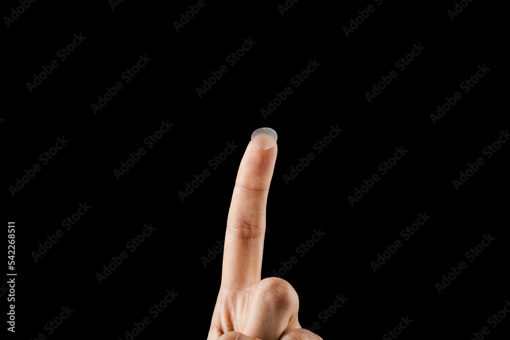 Close-up round acne patch on finger on black background. Acne patches for treatment of pimple and rosacea close-up. Facial rejuvenation cleansing cosmetology. Close-up round acne patch on finger on black background. Acne patches for treatment of pimple and rosacea close-up. Facial rejuvenation cleansing cosmetology.