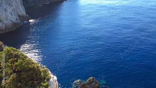 A tilting upward shot of a lighthouse built on a cliff top at the cape of an island. photo