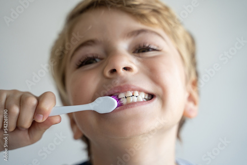 Cute child brush teeth toothbrush, smiling over white background. Studio shot. Dental hygiene, morning routine, lifestyle, tooth care, children health. Close up, soft focus.