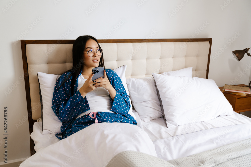 Young beautiful asian thoughtful woman in glasses with phone Young beautiful asian thoughtful woman in glasses with phone