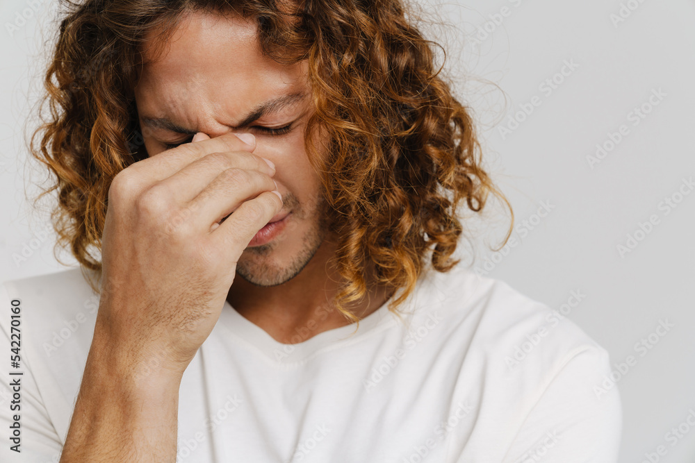 Ginger man with headache frowning and holding his nose bridge Ginger man with headache frowning and holding his nose bridge