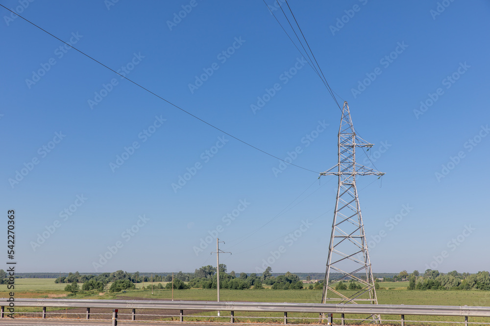 A road, a field of electric wires and a blue sky in summer.