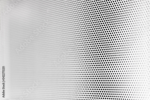 White grill texture with little circular holes with degraded focus in perspective to the left side