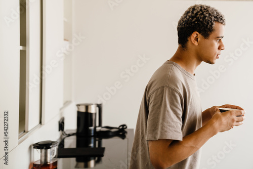 Tableau sur toile Black young man drinking coffee while having breakfast at home