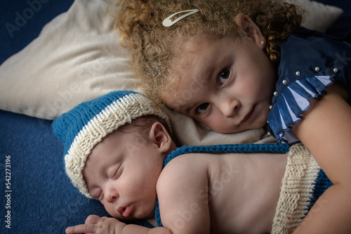 Little girl hugging her newborn brother