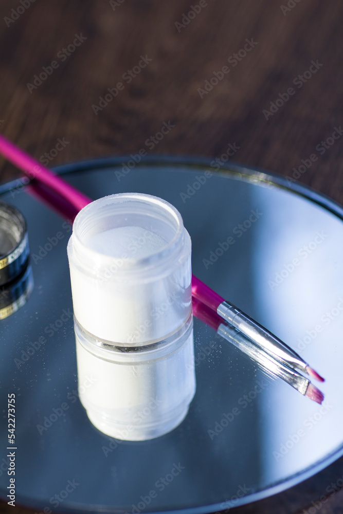 White acrylic powder to strengthen the nail plate and a brush in the reflection of the mirror White acrylic powder to strengthen the nail plate and a brush in the reflection of the mirror